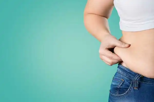 Image of woman pinching her love handles to show weight gain Wrexham